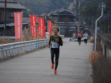 駅伝旗を背に走るランナー